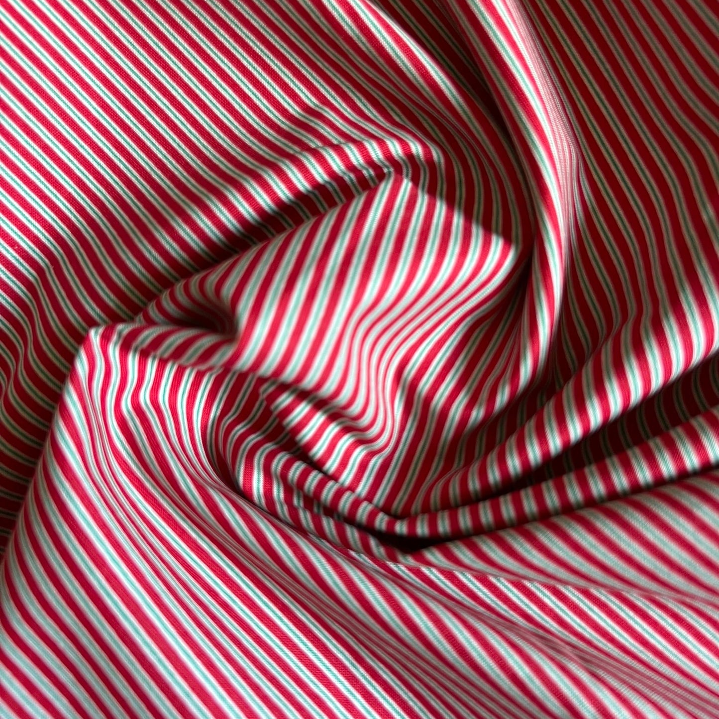 Red, white, and black diagonal striped fabric draped in soft folds.